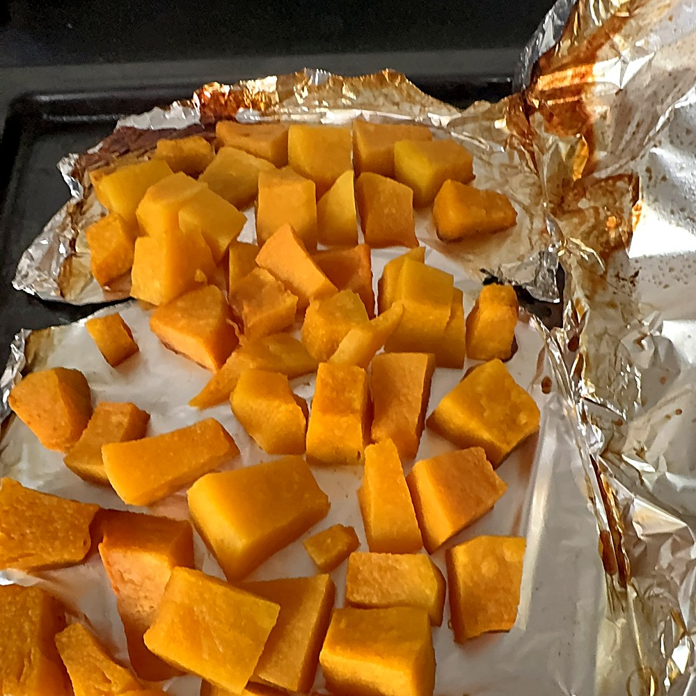 Roasted pumpkin, deep gold with caramelised edges, cooling on the tray