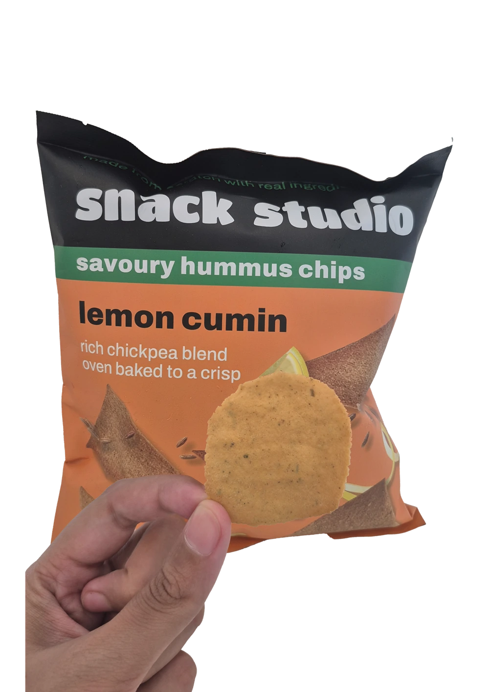Holding up a Snack Studio lemon cumin hummus chip in front of the packet